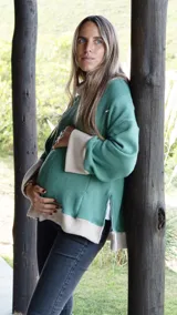 Sweater tejido color verde agua con cuello alto y puños en color crema. Tiene corte oversize y cierres verticales invisibles para amamantar.