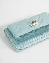 Billetera negra de cuerina con diseño acolchado, formato fichero, bolsillo frontal con broche y botón, cierre superior circundante y monedero interno con cierre.