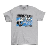 Remera gris de algodón con estampado frontal de la banda Turnstile. El diseño incluye la frase "Live and in the flesh!", el nombre "Turnstile" en letras grandes, y la frase "Baltimore Hardcore" con el logo de EMEXEM. La imagen muestra a un cantante con micrófono y otra persona saltando sobre un fondo azul.
