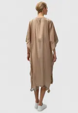 Túnica color crudo de algodón, corte holgado, con cuello en V con lazo y borlas, y detalle de puntilla en el ruedo.