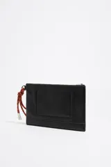 Neceser negro de piel con estructura blanda, asa de mano de cordón extraíble, logo metálico, acabados metálicos plateados, bolsillo interior y cierre con cremallera. Interior con etiqueta de tejido BIMBA Y LOLA.