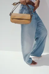 Bolso bandolera color caramelo, con doble asa: una asa larga regulable y una asa de hombro. Tiene bolsillo interior con cierre mediante cremallera metálica y solapa con cierre imantado.