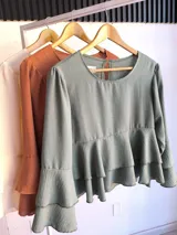 Blusa color ladrillo con corte a la cintura y volados. Mangas largas acampanadas.
