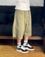 Bermuda de corte baggy color verde con efecto gastado. Presenta costura vertical trasera en cada pierna y detalle artesanal visible en el bajo. Incluye un cordón extra confeccionado en la misma tela.