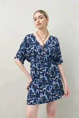 Vestido corto color marrón con estampado de hojas blancas, escote en V, mangas cortas y cintura marcada.