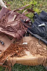 Bolso maxi negro de cuero con flecos y botón de guampa. Tiene bolsillo interior y cierre metálico.