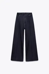 Jeans de tiro alto, pierna ancha y largo al tobillo, en denim celeste claro con efecto lavado. Presenta costura marcada en el centro de cada pierna y cierre frontal con cremallera y botón.