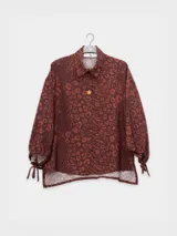 Camisa de manga 3/4 con puños elastizados, cuello camisero y estampado de figuras humanas y peces en color crema sobre fondo negro.