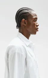 Camisa de manga corta, color blanco, confeccionada en popelín de algodón con silueta oversize. Posee dos bolsillos frontales, uno con solapa y otro con ojal y botón.