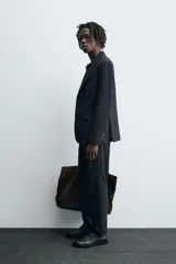 Blazer negro de lana con cuello de solapa de muesca, manga larga con puños abotonados, bolsillos de vivo en el pecho y de solapa en la cadera, bolsillo interior, aberturas en la espalda y cierre frontal con botones.