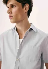 Camisa celeste con estampado de microcuadros, de manga corta, con cuello clásico y bolsillo en el pecho.