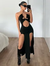 Vestido negro ajustado con cuello halter, abertura en el abdomen y dos tajos laterales altos.