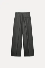 Pantalón ancho gris con textura de espiga, tiro alto, doble cintura elástica ajustable con cordón, pinzas frontales, bolsillos delanteros y falso bolsillo de vivo en la espalda.
