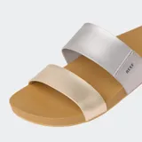 Sandalias Reef Cushion Vista con dos tiras, una plateada y otra dorada, sobre una base color caramelo.