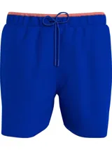 Bañador azul eléctrico de largo medio, con cintura elástica ajustable con cordón, ribete naranja en la cintura y logo de Tommy Hilfiger bordado en la parte trasera.