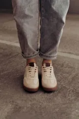 Zapatillas bajas de cuero color marrón con suela de goma color caramelo y cordones marrones.