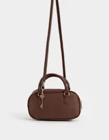 Cartera bowling color marrón chocolate, de cuero sintético, con doble asa corta, correa larga regulable y desmontable, y charm colgante.