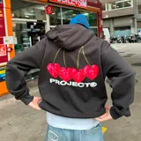 Hoodie gris con capucha, corte oversize y estampado en la espalda de cuatro cerezas rojas con letras en blanco y el logo de la marca.