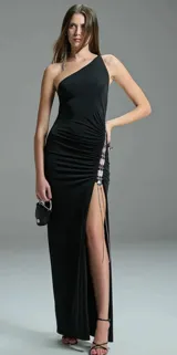 Vestido largo negro de jersey con un solo hombro, drapeado lateral y abertura en la pierna. Presenta detalle de cuentas metálicas en el lateral.