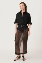 Camisa negra de algodón con cuello solapa, manga larga tipo murciélago con puños abotonados, hombros caídos, bolsillo de parche en el pecho, pinzas en la espalda y cierre frontal con botones.