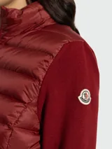 Cardigan híbrido Moncler confeccionado en lana virgen con panel frontal acolchado tipo puffer. Presenta cuello alto, cierre frontal de cremallera bidireccional y el icónico parche del logo en la manga izquierda.