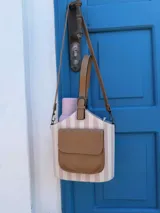 Matero con forma de balde, confeccionado en material símil cuero beige con estampado de rayas verticales en verde militar. Posee bolsillo frontal, asa de mano y correa larga desmontable.