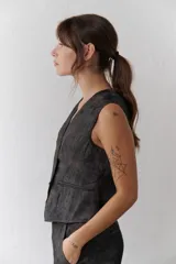 Chaleco grafito con cuello en V, cierre frontal con botones y bolsillos ribeteados.