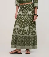 Pollera larga (midi/maxi) de tejido piqué, color verde oscuro con estampado en blanco/beige de motivos tropicales y palmeras. Presenta un diseño con fruncido en la parte inferior.