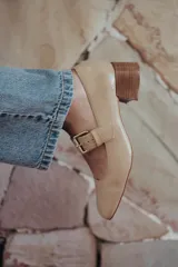 Zapatos de charol color beige con taco bloque de madera y tira sobre el empeine con hebilla dorada.