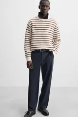 Sweater de punto color crudo con rayas horizontales marrones, de corte relaxed fit, cuello redondo y mangas largas con terminaciones en rib.