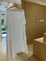 Vestido de lino blanco estilo túnica, con escote en V, manga corta, bolsillos laterales y largo irregular.