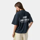 Remera azul de corte amplio con logo y texto estampados en blanco en la espalda.