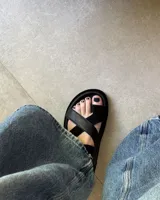 Sandalia marrón de cuero vacuno con tiras cruzadas y ajuste con hebilla al tobillo.