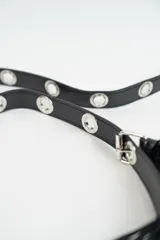 Bandolera negra de cuero sintético con flecos y correa de hombro con estampado de logos.