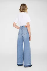 Jean de corte baggy y pierna ancha, confeccionado en denim de algodón sin elasticidad con lavado vintage medio. Presenta tiro alto, cierre con cremallera, diseño clásico de cinco bolsillos y ruedo al corte con efecto desgastado.