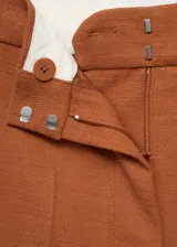 Pantalón de vestir color ladrillo, de corte recto y tiro alto, confeccionado en mezcla de algodón y lino. Presenta cierre frontal con cremallera, doble gancho y botón interior, dos bolsillos laterales y forro interior.
