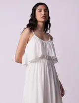 Vestido midi blanco de gasa bambula marca Lily Black, con escote redondo, breteles regulables y lazo de ajuste. Presenta una sobrecapa en el torso y un forro interno a tono. El largo de la espalda es mayor al largo delantero.