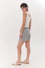 Short de tela color blanco con rayas verticales negras, cintura elastizada con cordón ajustable.