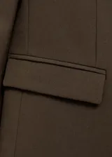 Blazer marrón oscuro de corte recto, con solapas de muesca, cierre frontal con botones, mangas largas con puños abotonados y dos bolsillos con solapa en la parte delantera.