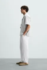 Pantalón de vestir blanco, confeccionado en lino, de corte recto, con bolsillos laterales y traseros. Se ajusta a la cintura con botón y cierre.
