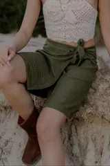 Minifalda celeste de lino y poliéster, con corte cruzado y lazo lateral.