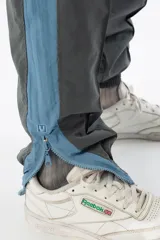 Pantalón de jogging gris con forro interno de red, bolsillos laterales con cierre, cierres en los tobillos y logo bordado.