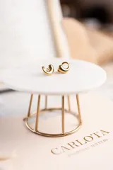 Par de aros dorados con forma de coma, de acero quirúrgico con baño de oro.