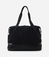 Bolso tipo maleta de tamaño grande en color negro, confeccionado en una mezcla de poliuretano y poliéster. Presenta cierres de cremallera plateados contrastantes, un bolsillo frontal con cierre y un compartimento inferior independiente con cierre. Incluye asas de mano dobles y una correa de hombro larga, ajustable y extraíble.