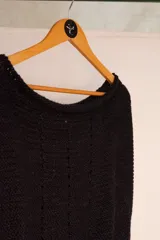 Chaleco negro tejido a mano en dos agujas con hilado 100% baby alpaca, ligeramente oversize, de hombros anchos y cuello tipo bote, con puntos calados en frente y espalda y tajos a los lados en el bajo.