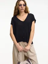 Remera negra con botones en la parte delantera y escote amplio, de mangas cortas. Confeccionada en viscosa y lino.
