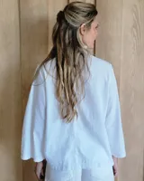 Camisa azul con cuello mao y volados en el frente, mangas 3/4 con puños anchos y cierre frontal con botones.