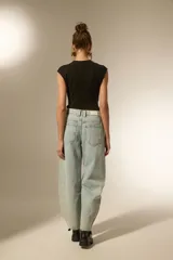 Pantalón de jean negro de corte ancho y tiro bajo, con detalles de tachas metálicas en los bolsillos delanteros y a lo largo de las costuras laterales.