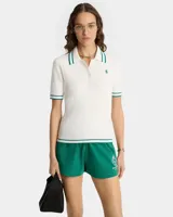 Remera polo de punto color blanco con patrón de cable pequeño, logo bordado en el pecho y rayas contrastantes en verde en cuello y mangas. Cierre frontal con tres botones.