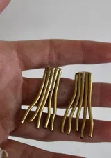 Par de aros de bronce con forma abstracta de líneas onduladas.